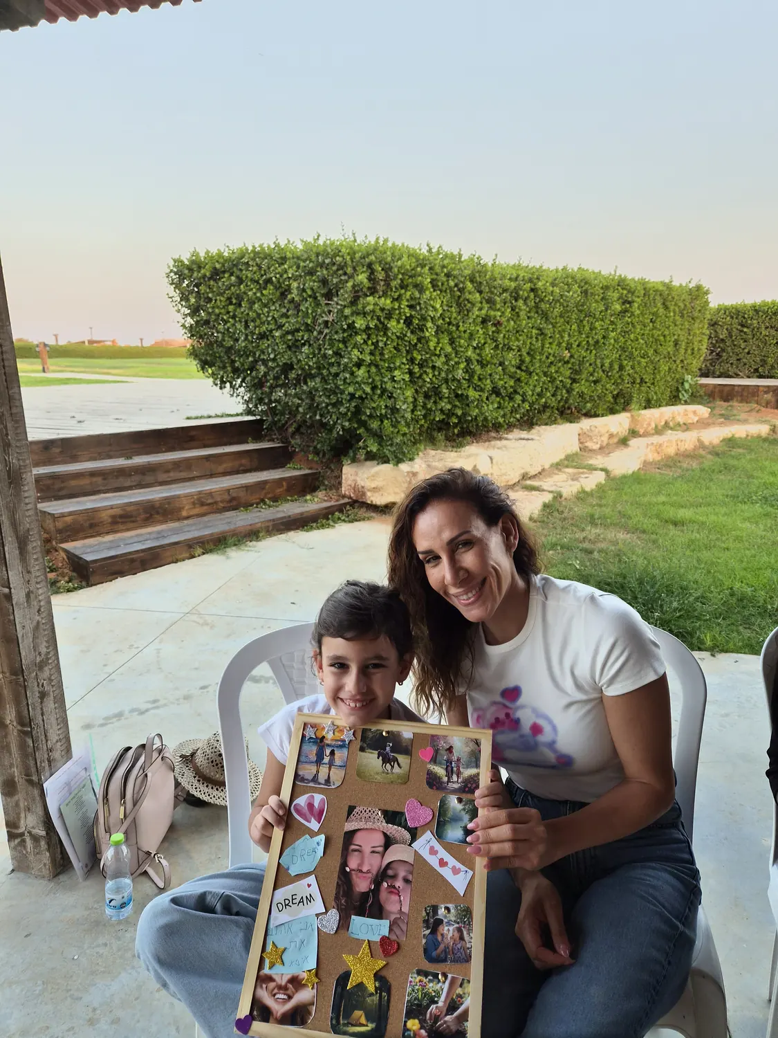 אמא ובת יושבות יחד ומציגות את לוח היצירה שהכינו